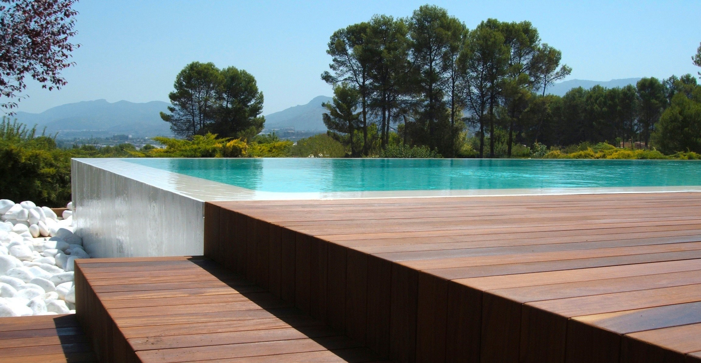 Piscina desbordante con tarima de madera construida por Construcciones Guaita